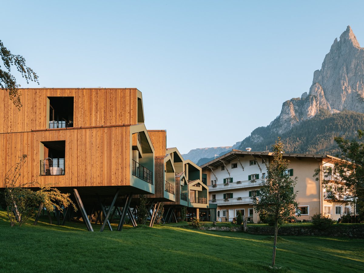 Moderne Chalets neben traditionellen Gebäuden mit Bergblick Moderne Chalets und traditionelle Gebäude vor Bergkulisse