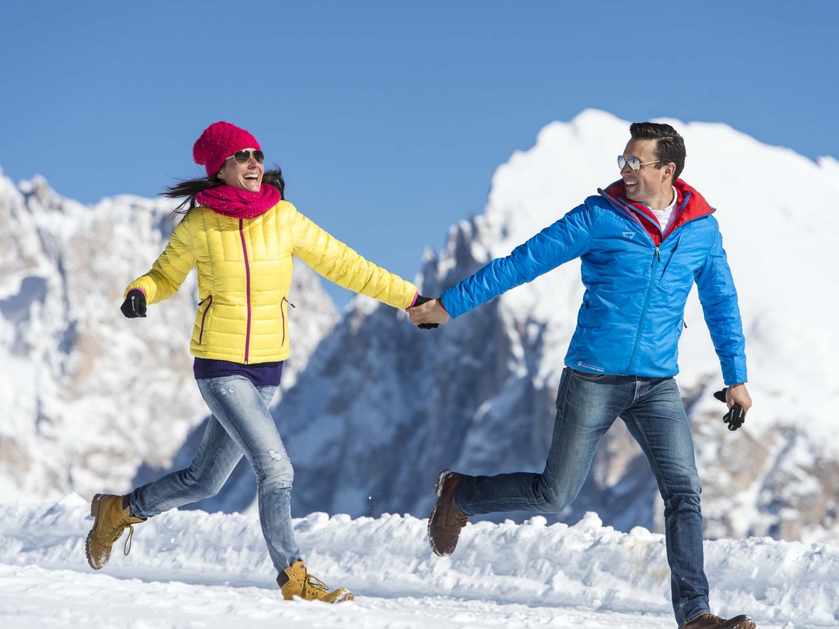 Fröhliches Paar in warmer Kleidung beim Winterspaziergang Paar beim Spazieren im Schnee