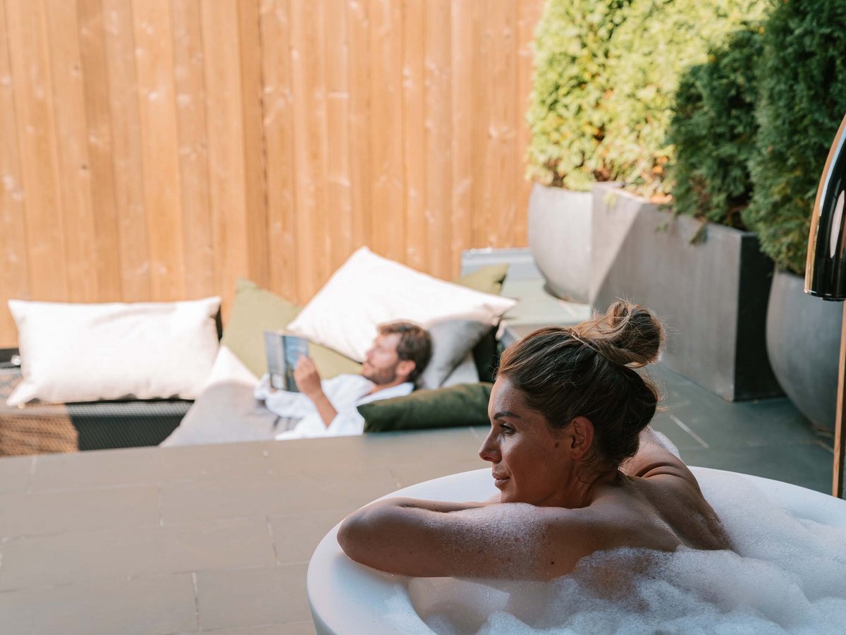 Entspannung in Badewanne und Ruheraum eines Chalets Frau in Badewanne, Person im Entspannungsbereich