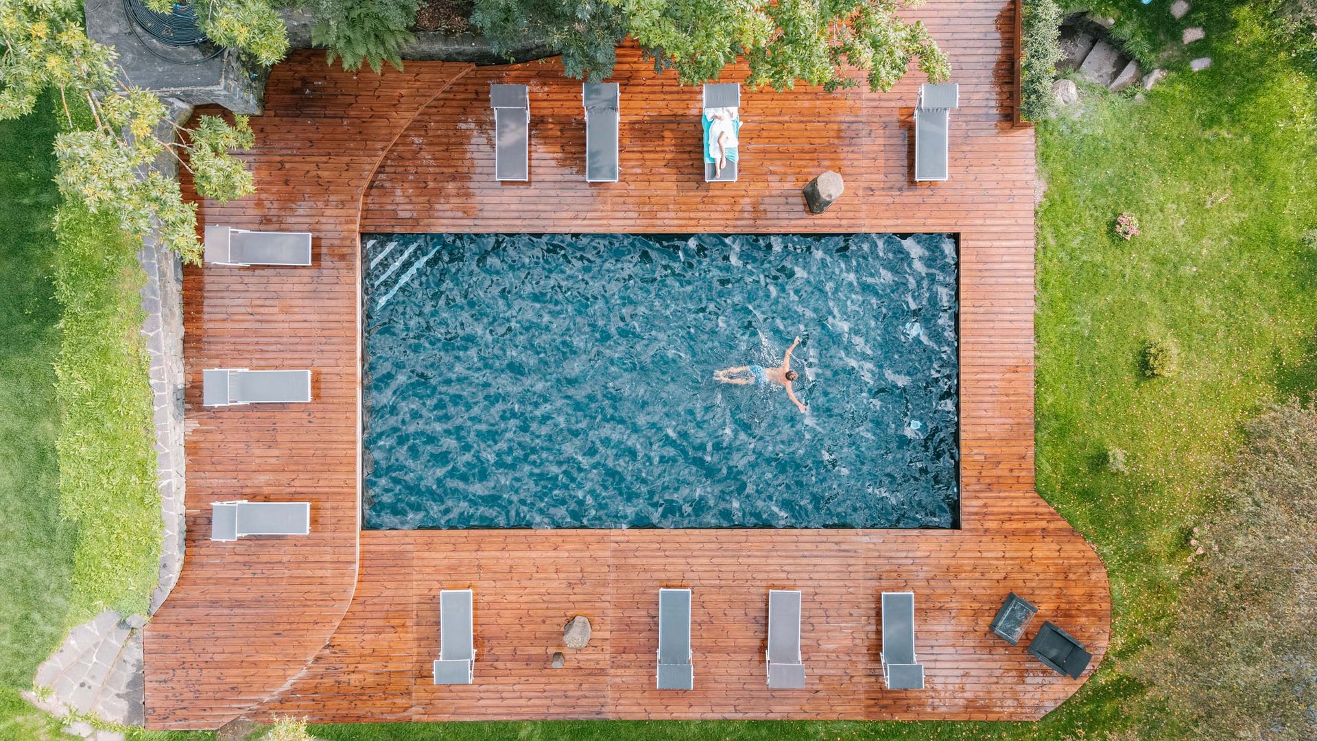 Außenpool mit schwimmender Person und Liegestühlen
