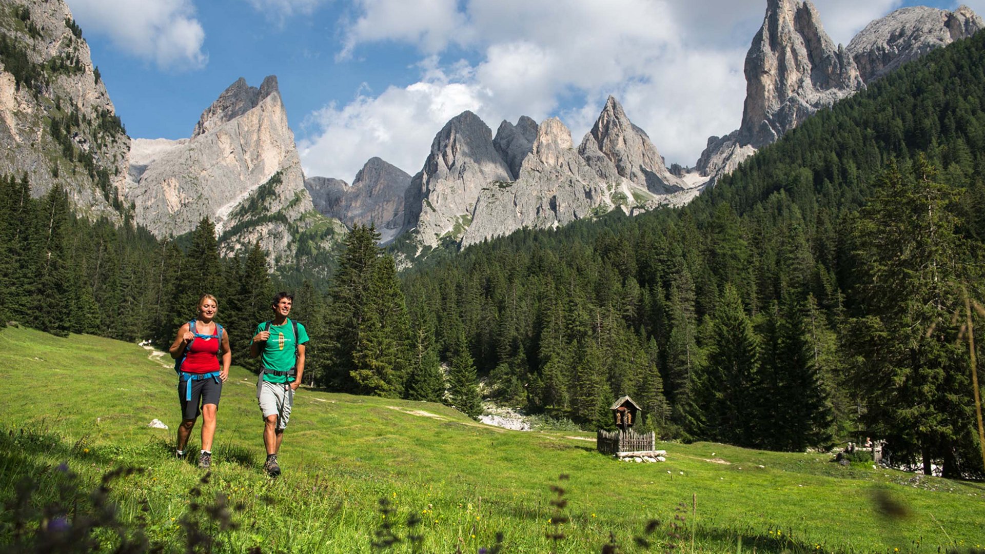 Zwei Personen beim Wandern in grüner Berglandschaft